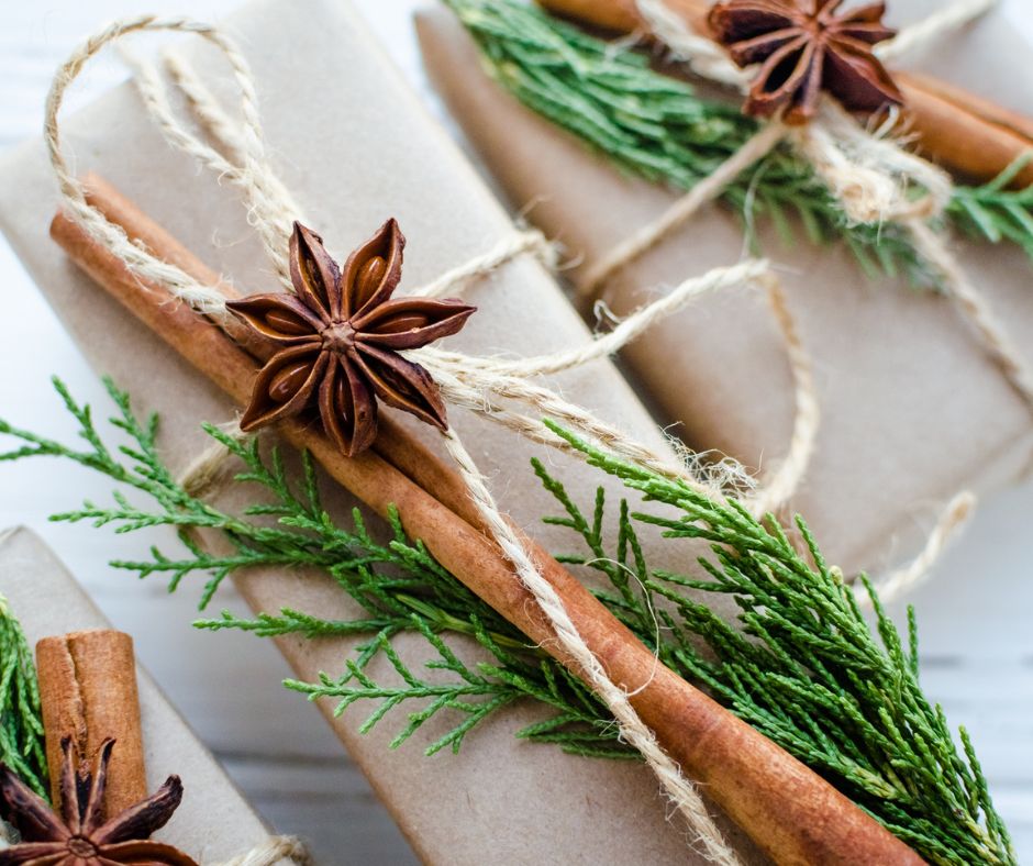 Craft paper wrapped holiday gifts with natural decorations of dried anise, cinnamon sticks, evergreen fronds and twine.