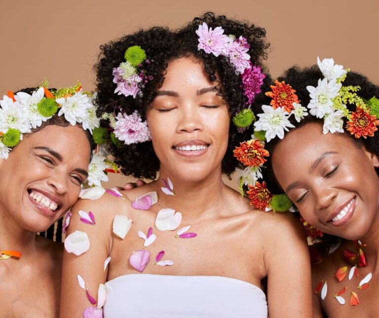 Three women relaxing with flowers in their hair and petals on their shoulders.