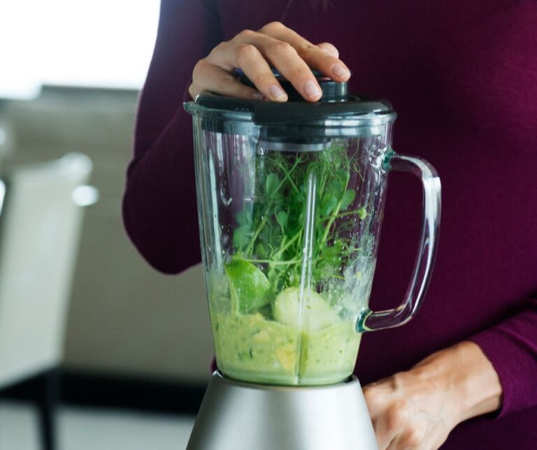 A person make a smoothie in a glass blender.