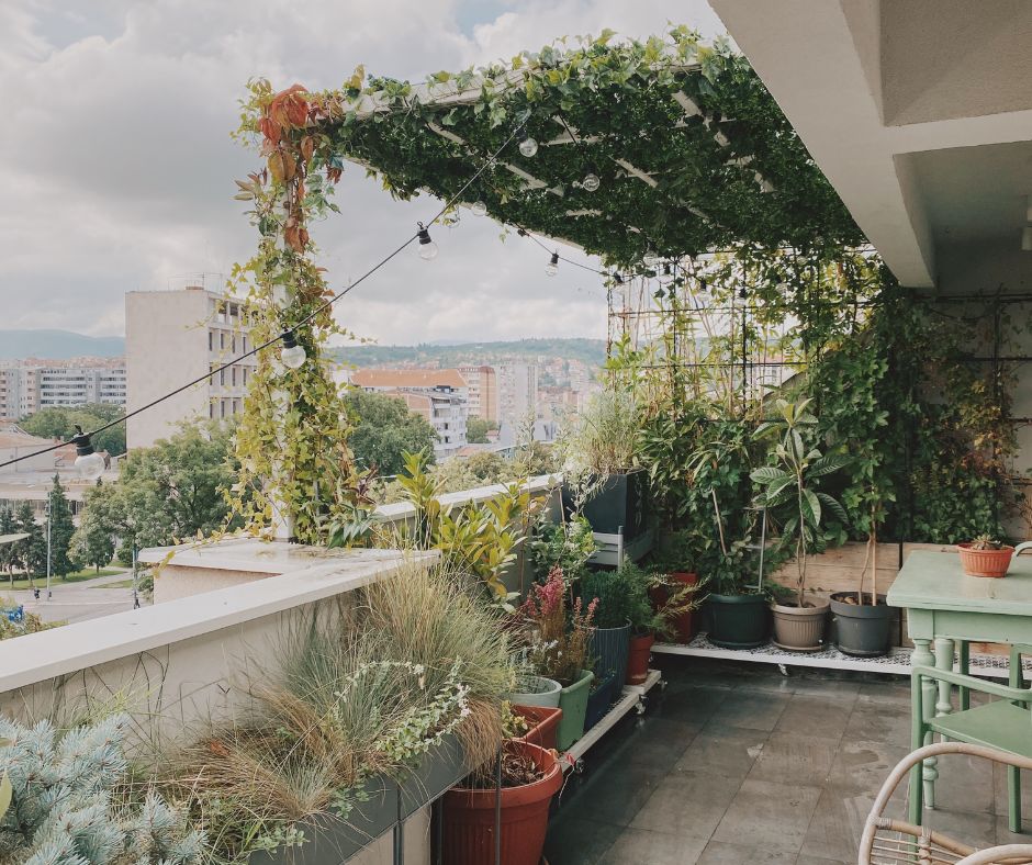 A private balcony garden made up of a mix of potted plants and faux plant screening.