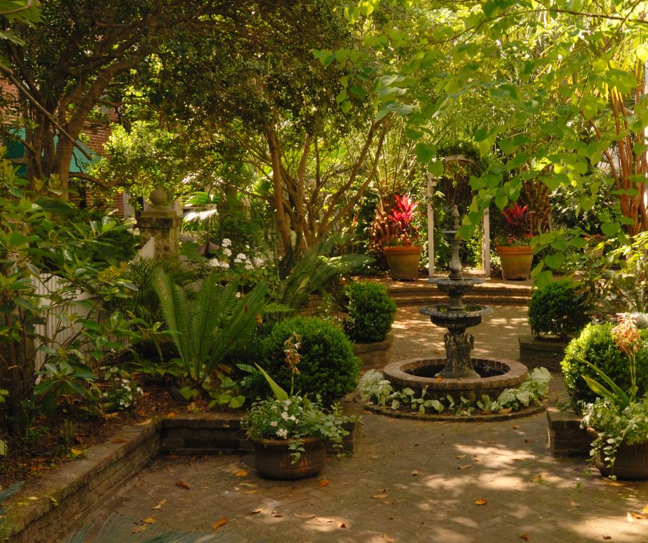 A southern courtyard container garden with shade provided by trees and a central water fountain.