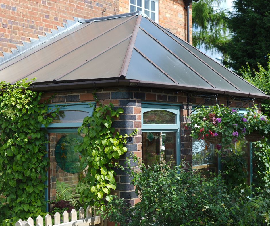 A well designed garden room with a metal roof attached to a brick home.