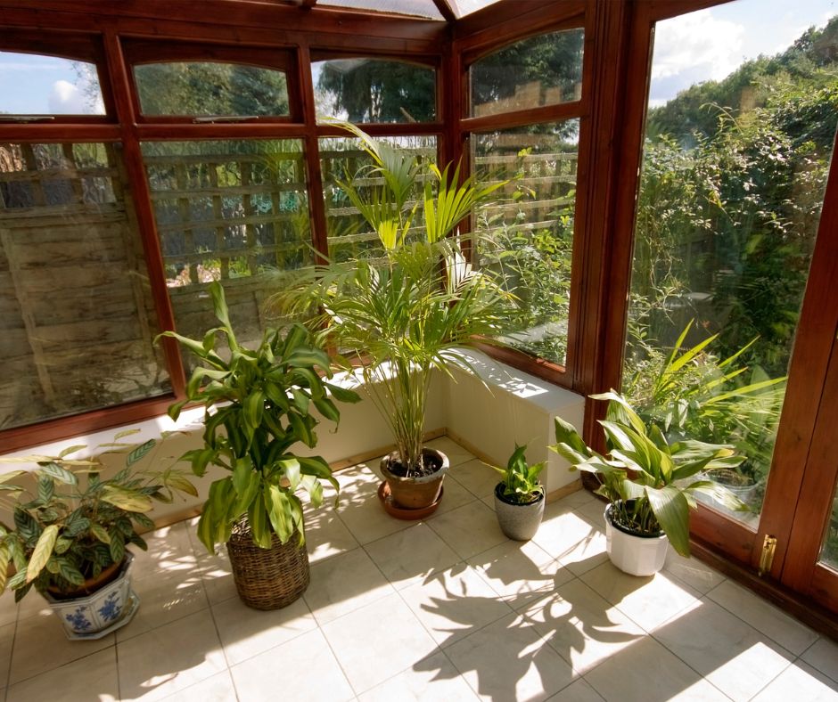 A sunroom with potted plants and wood framing.