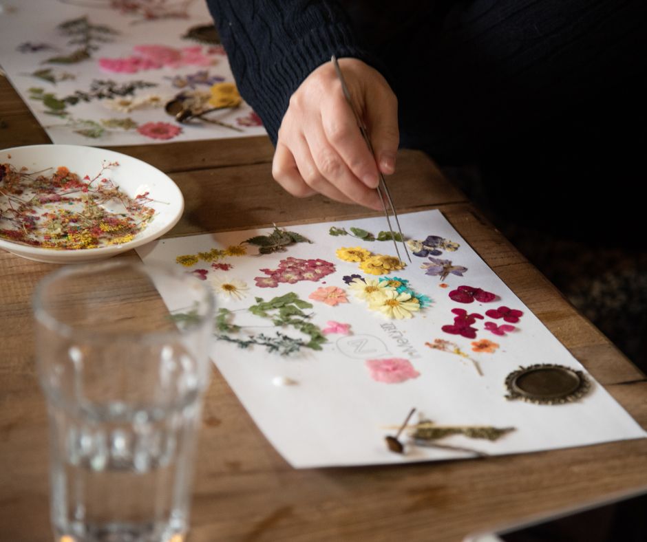A person removing pressed flowers from blotting paper with tweezers.