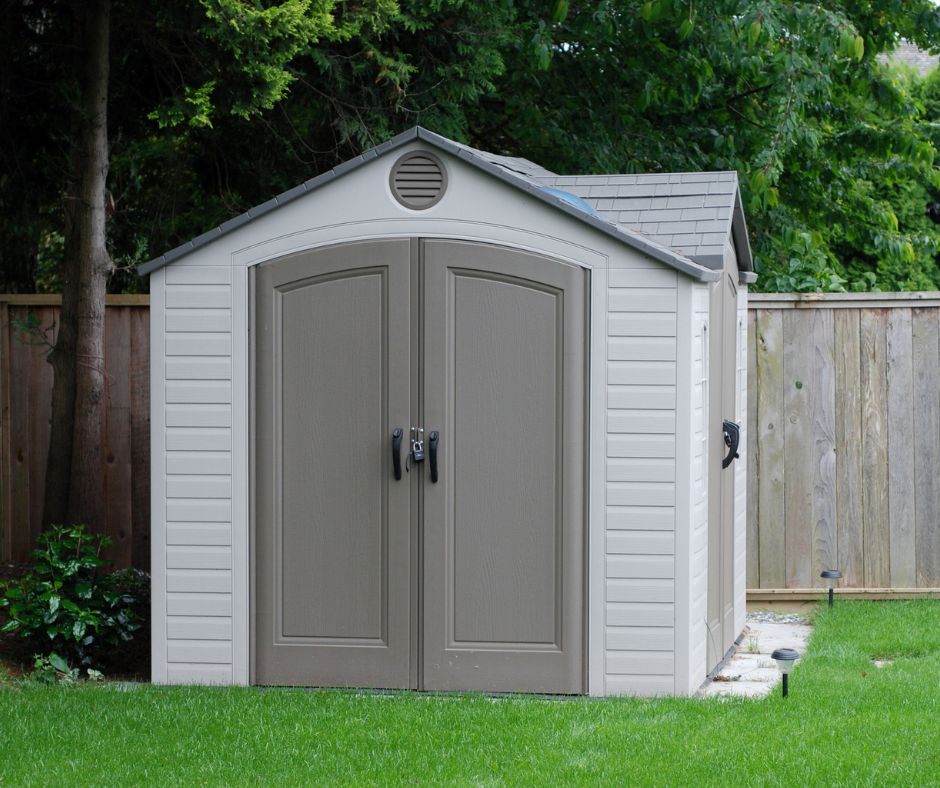 A grey resin backyard shed on green grass.
