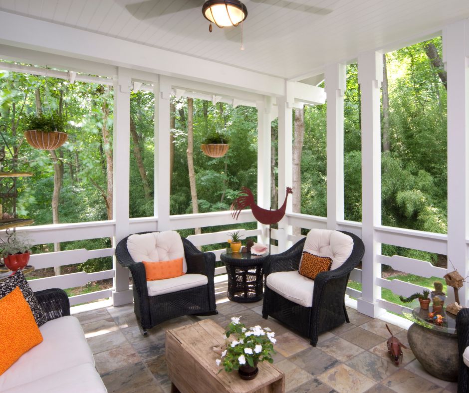 A covered patio with a comfortable wicker patio set and hanging baskets of plants.