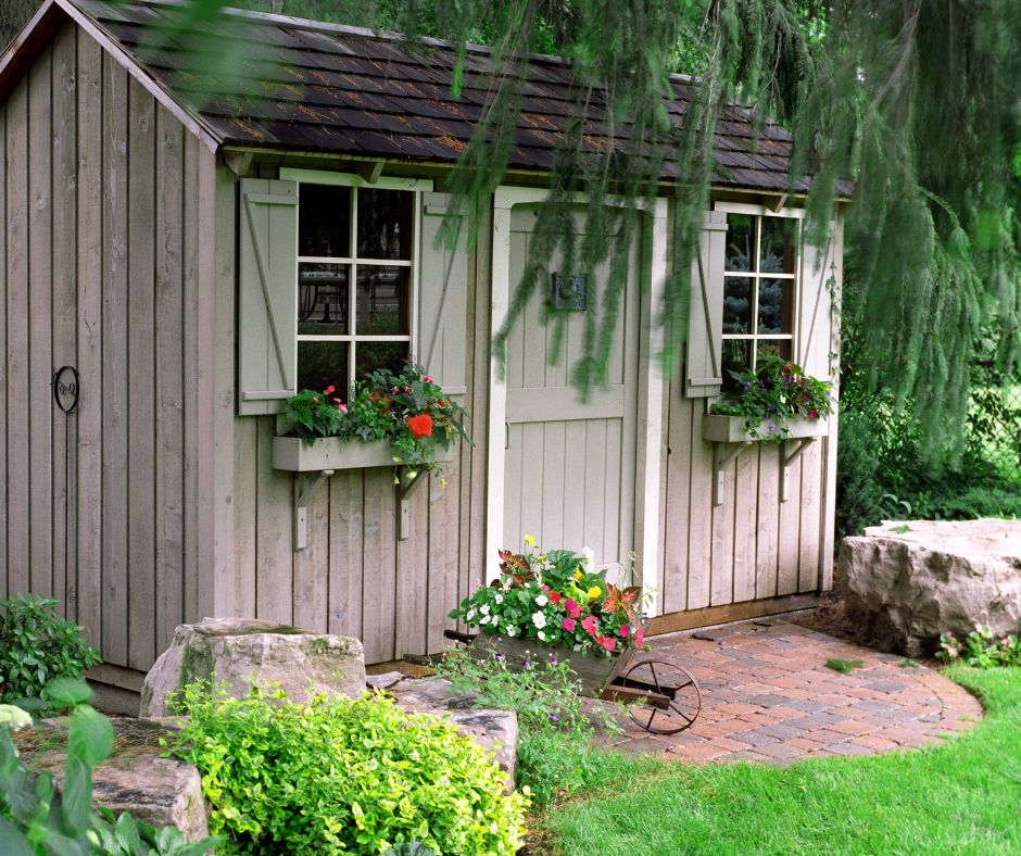 A wooden garden shed with windows and flower boxes.