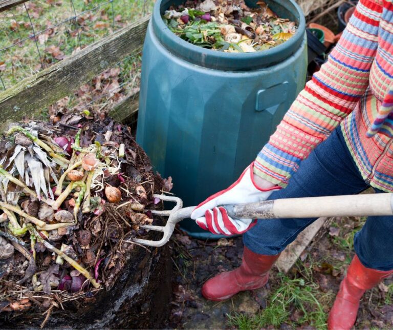 A gardener turning composting in a brightly colored sweater.