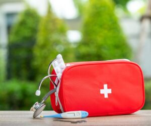 A red first aid kit on a table in a garden.