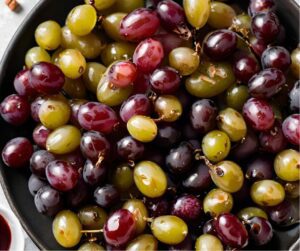 Red and green grapes seasoned and coated in olive oil ready to be roasted in the oven.