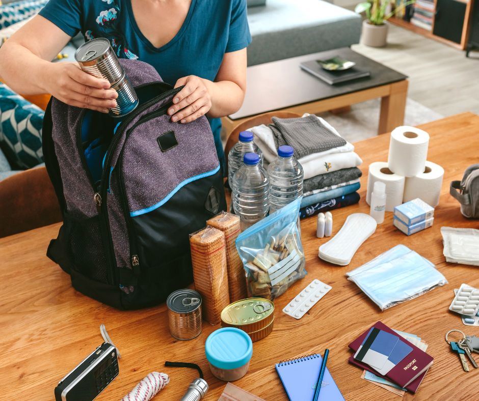 A person packing an emergency go bag with supplies.