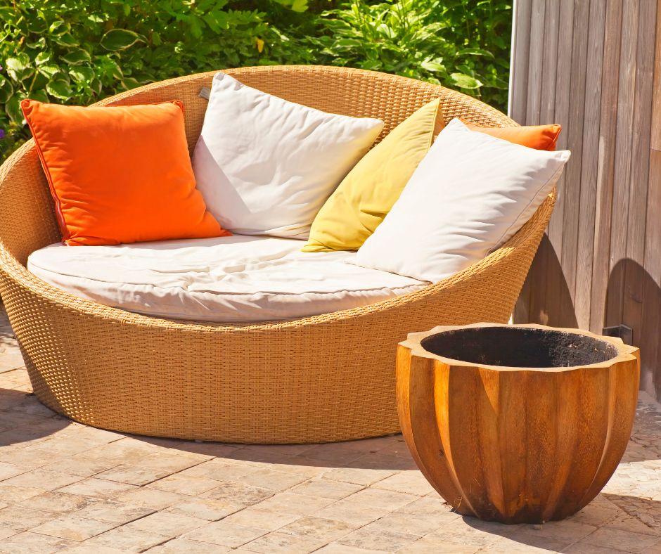 An oversized comfy patio chair next to a fire pit on a sunny patio.