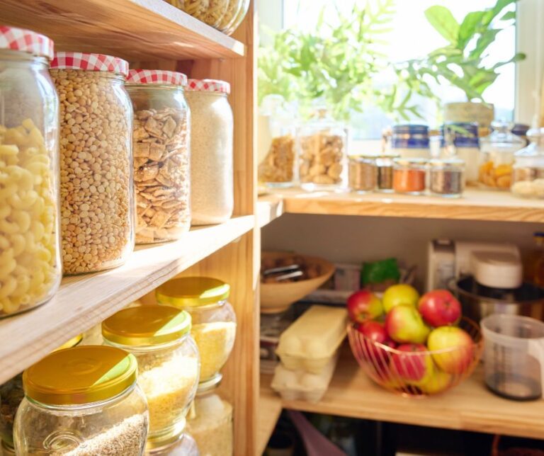 A wooden shelved pantry full of food in jars.