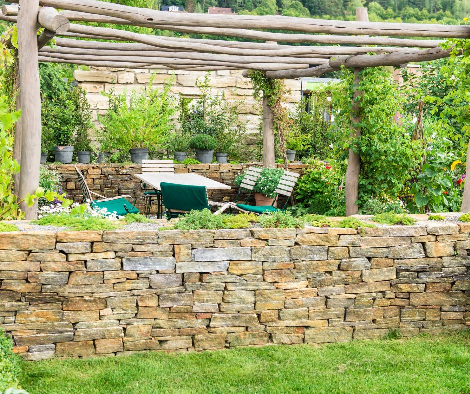 A rustic outdoor gathering spot surrounded by a low wall. Shade provided by raw wood beamed pergola.