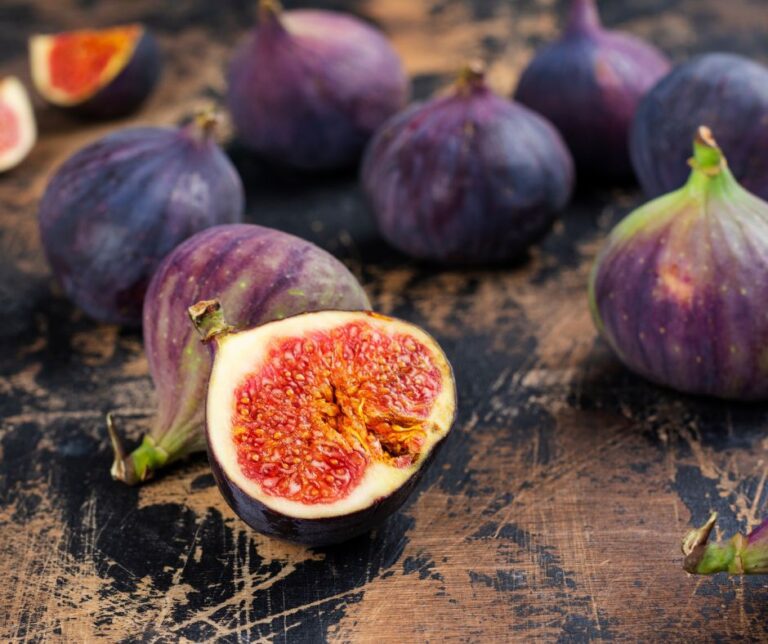 Ripe deep purple figs on a wooden table.