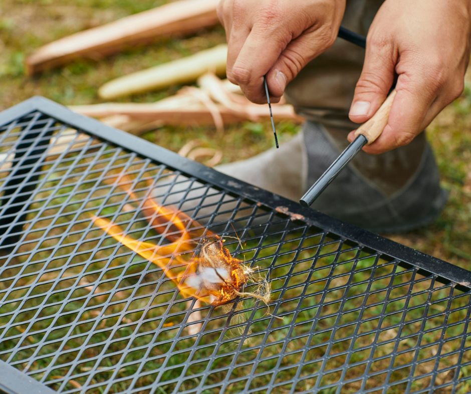 A person starting a camp cooking fire with flint.