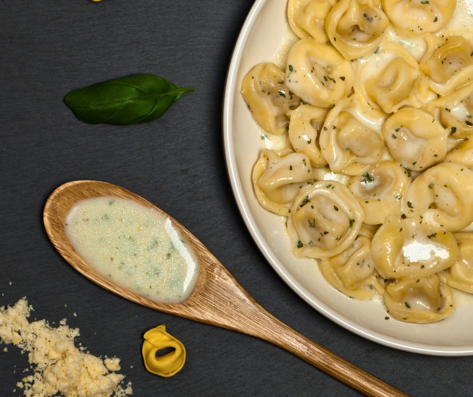 Pasta with basil alfredo sauce on top.