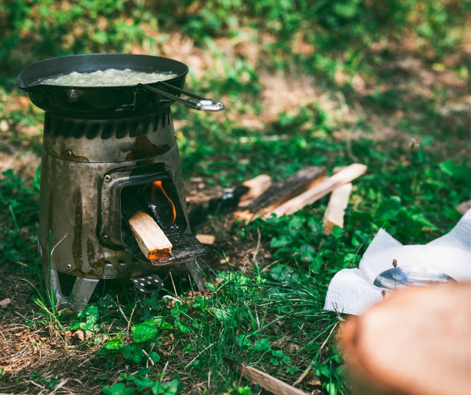 A person cooking on a portable wood stove.