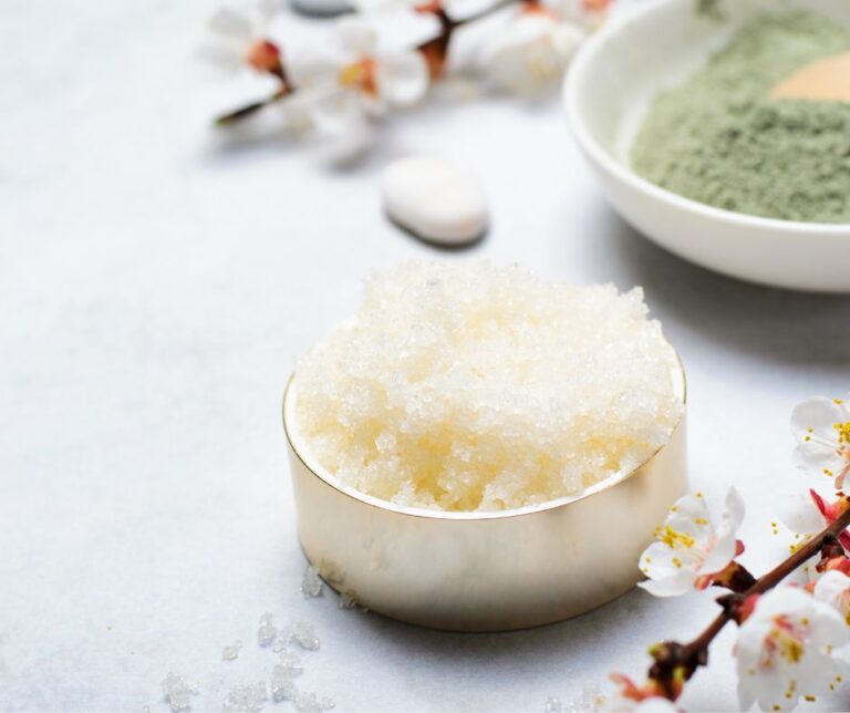 A bright light DIY lip scrub next to spring flowers.