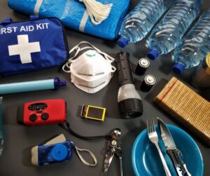 An assortment of emergency supplies and kits on a black table.