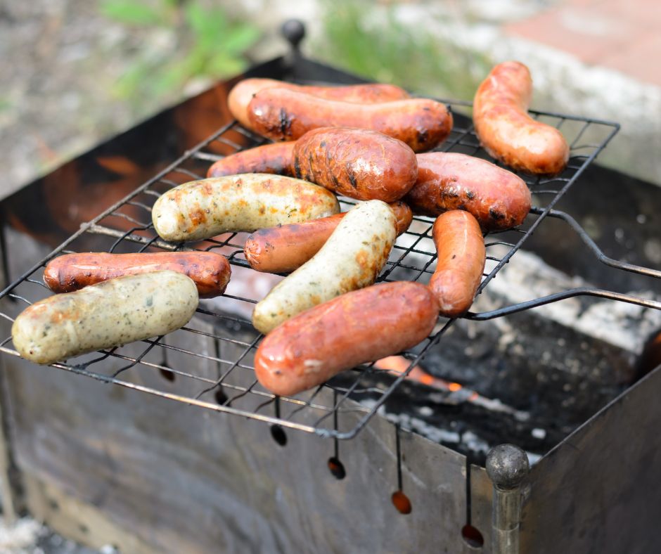 A person cooking sausages with a portable grill grate.