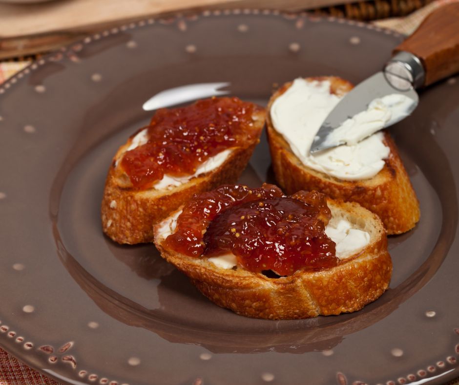 A plate of toast toped with creamed cheese and fig jam.