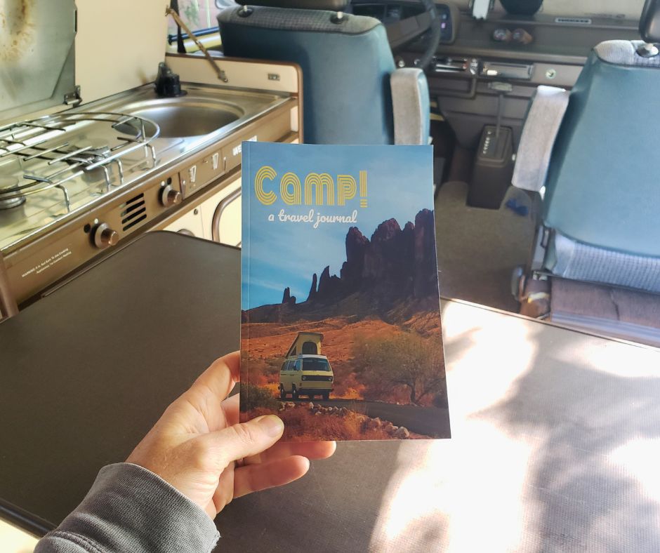 A person holding a camp journal in a camper van.