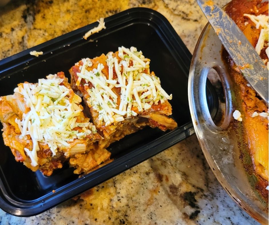 Two portions of baked ziti in a reusable freezer container.