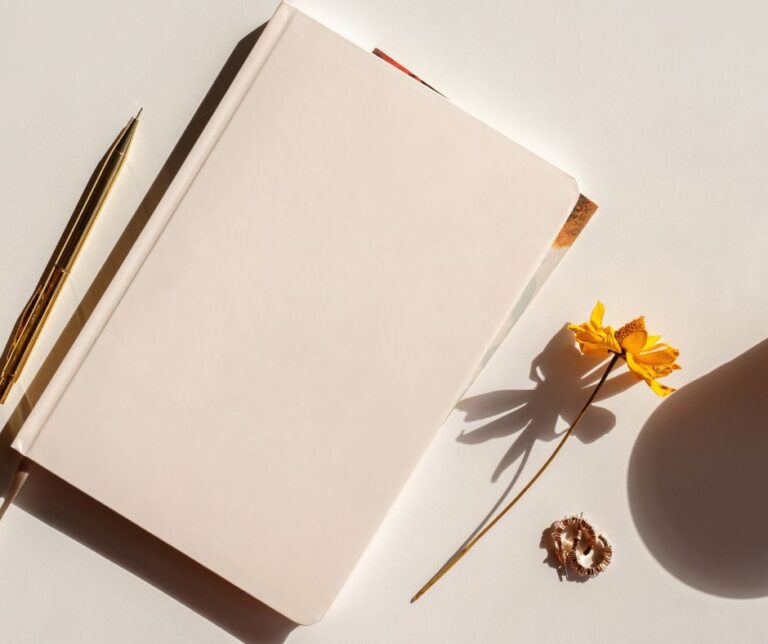A white journal next to an orange flower