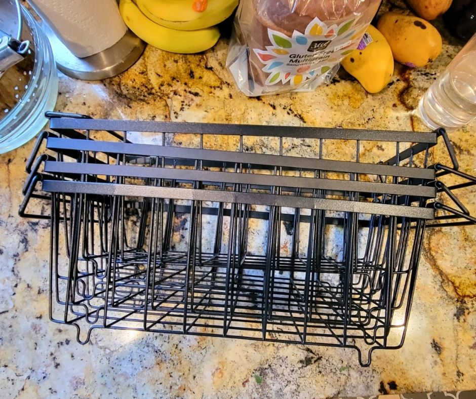 Four black metal wire deep freezer baskets on a marble kitchen counter.