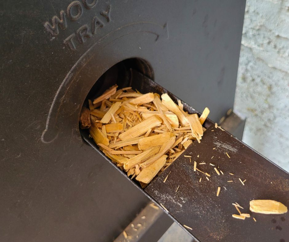 Wood chips being loaded into an electric patio smoker.