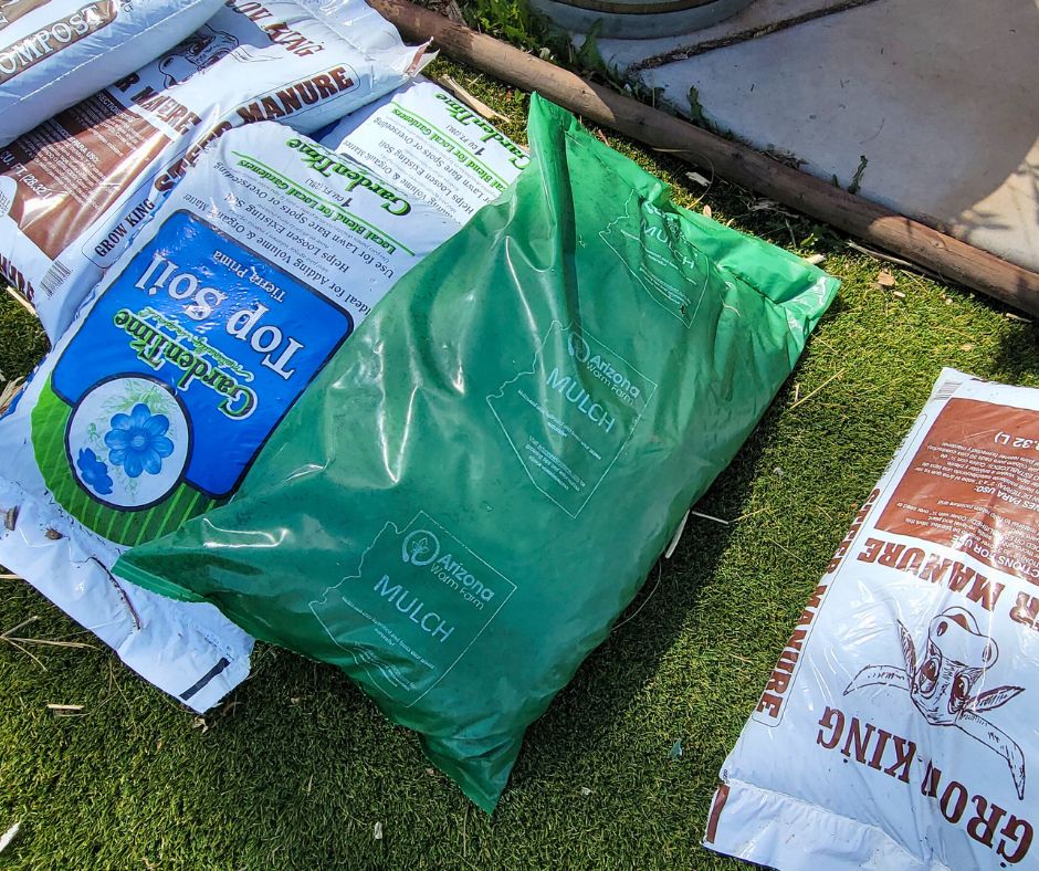 Bags of top soil, manure, mushroom compost, and mulch. on grass.