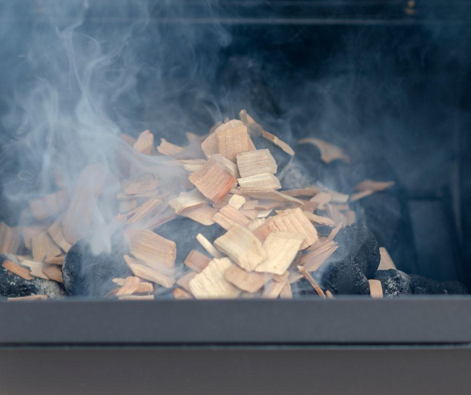 Wood chips on hot charcoals producing smoke.