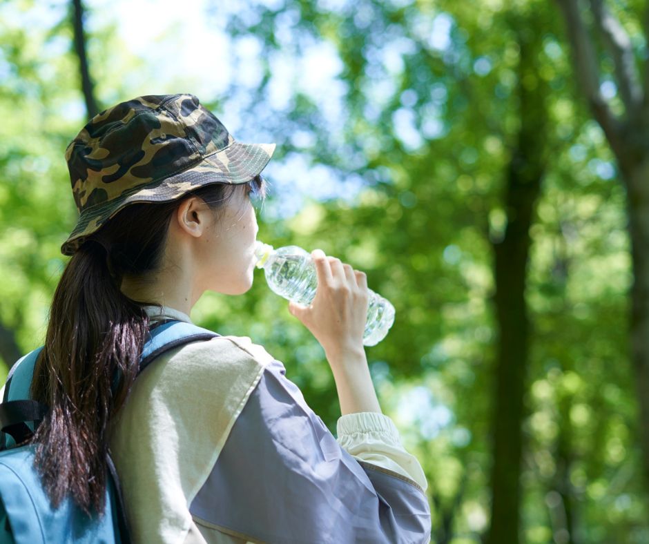 A hiker drinking water in a forest.