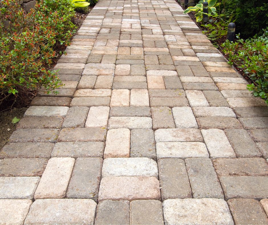 A backyard path made of pavers in various shades of grey.