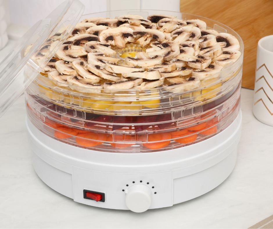 A round multi tiered countertop food dehydrator drying trays of mushrooms, beets, and carrots.