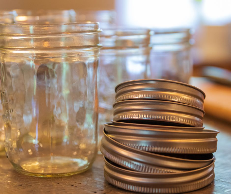 Several glass jars and aluminum canning lids.