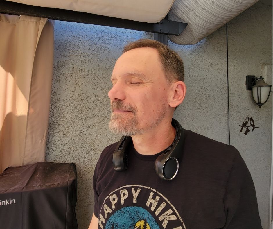 A man with his eyes closed enjoying a personal neck fan.