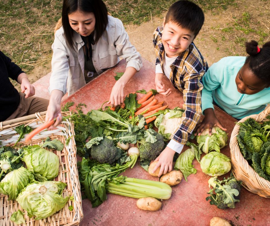 A woman and three kids sorting a fall harvest of cool weather veggies.