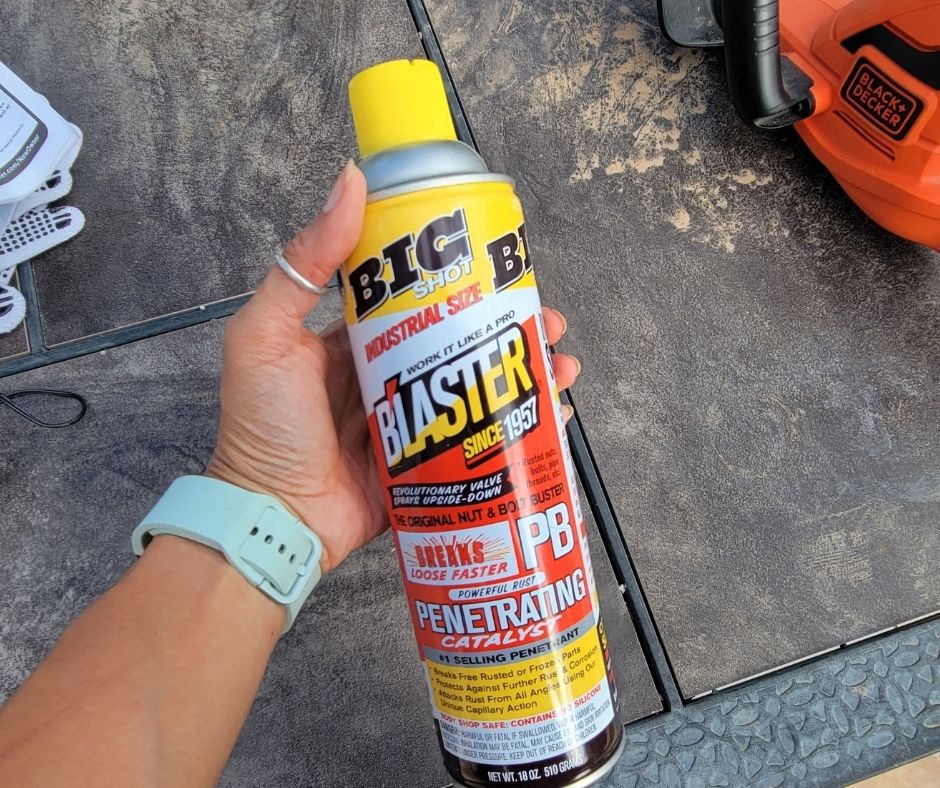 A hand hold a brightly colored can of rust remover.