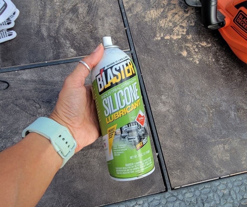 A hand holding a brightly colored can of silicone machine lubricant.