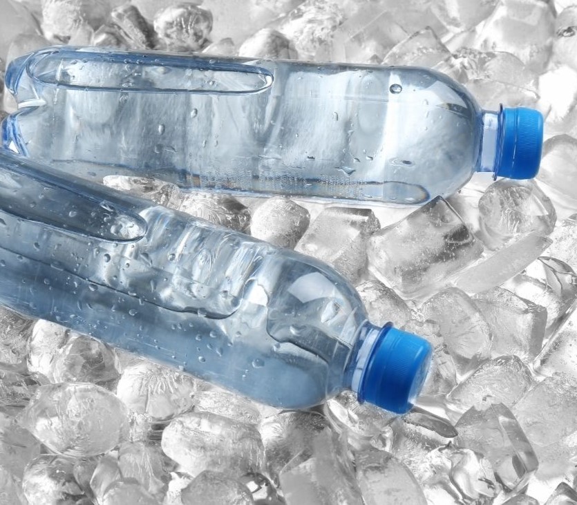 Two clear water bottles on a bed of ice.