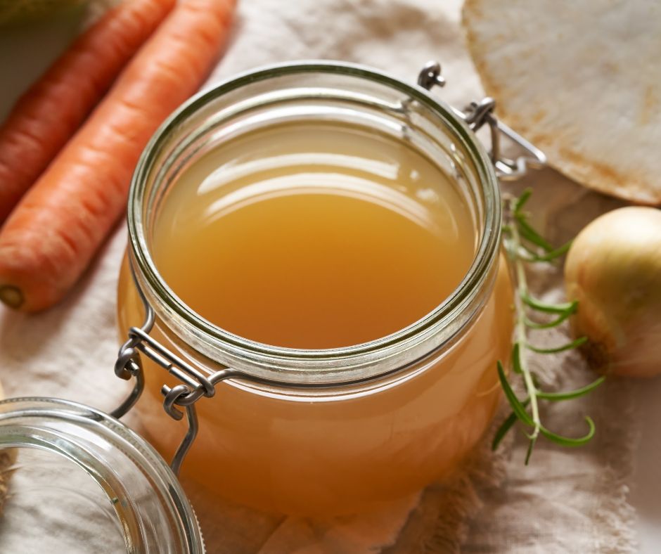 A jar of cooling vegetable stock in a kitchen.