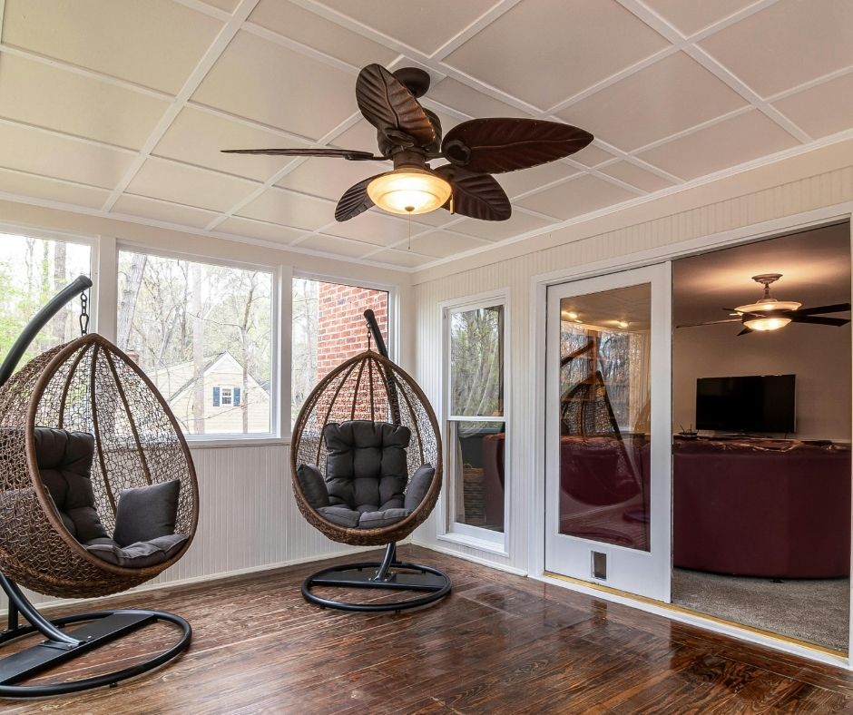 Two hanging chair and a ceiling fan in an enclosed patio.