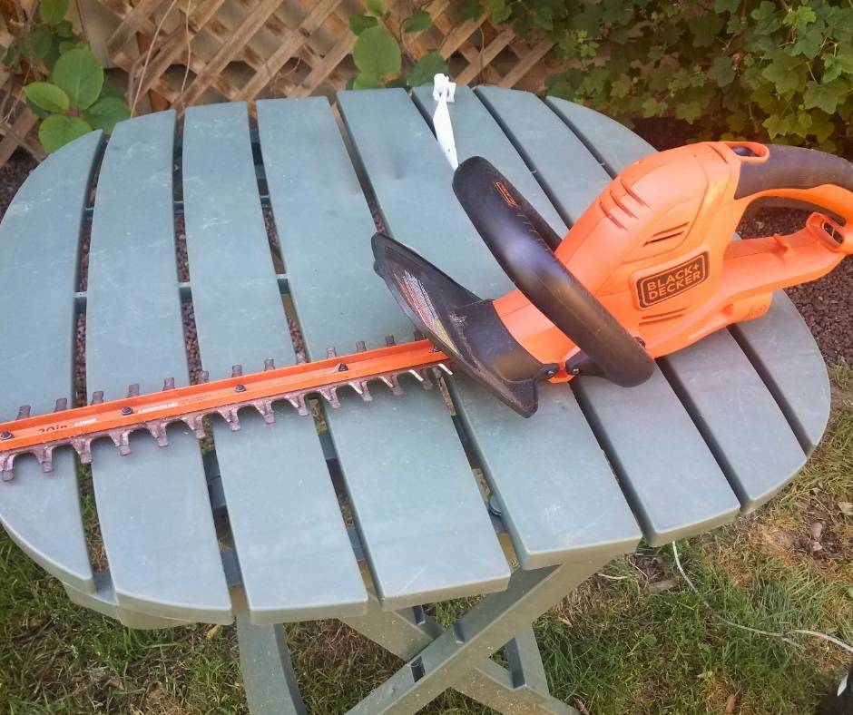A corded trimmer on a green garden table.