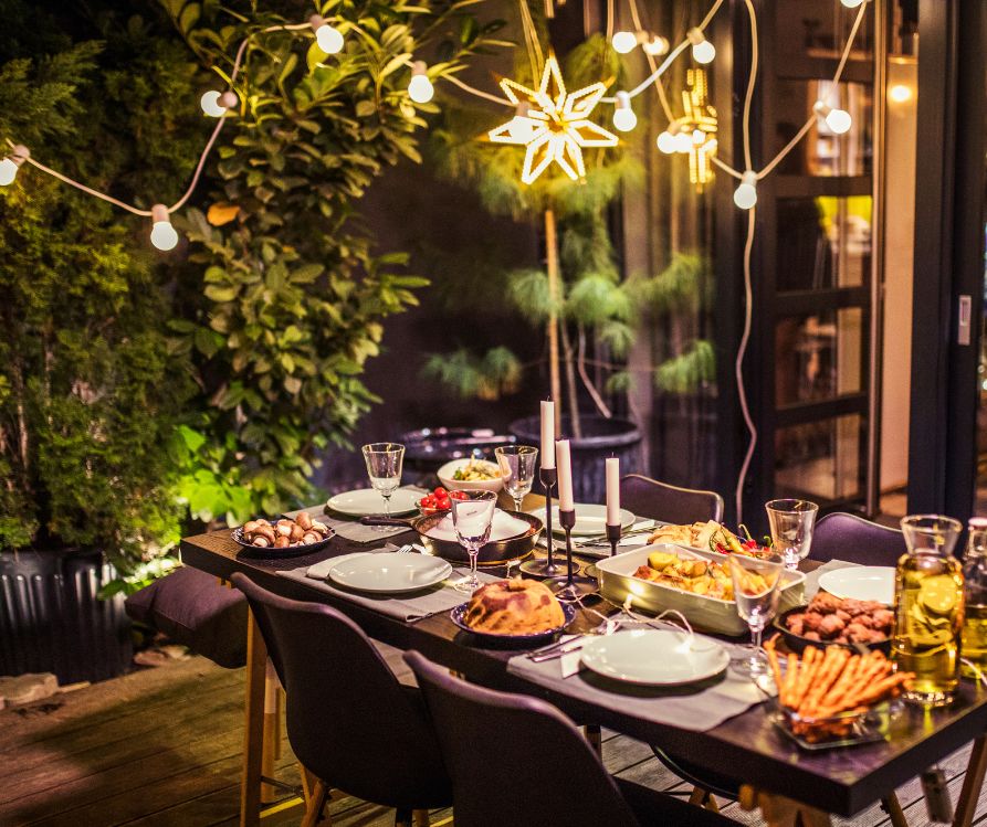A table set with fall decor, candles and seasonal dishes under string lights.