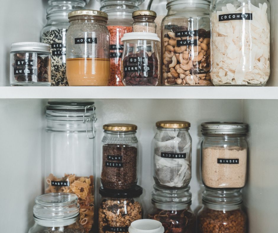 A pantry of dried foods in jars with black and white labels.
