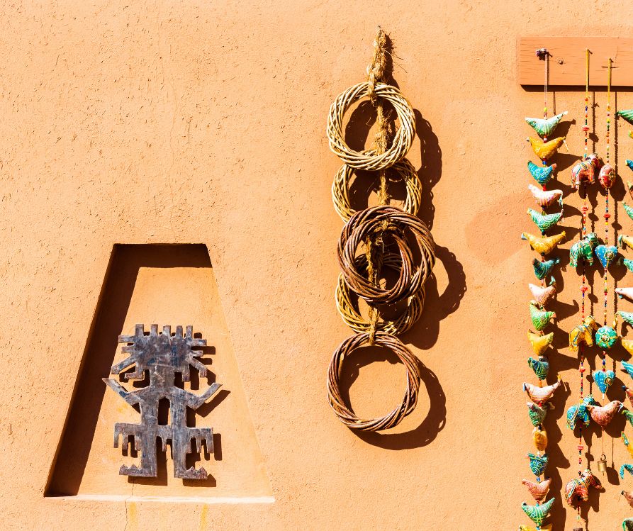 Native American and southwestern style art pieces displayed on an adobe wall.