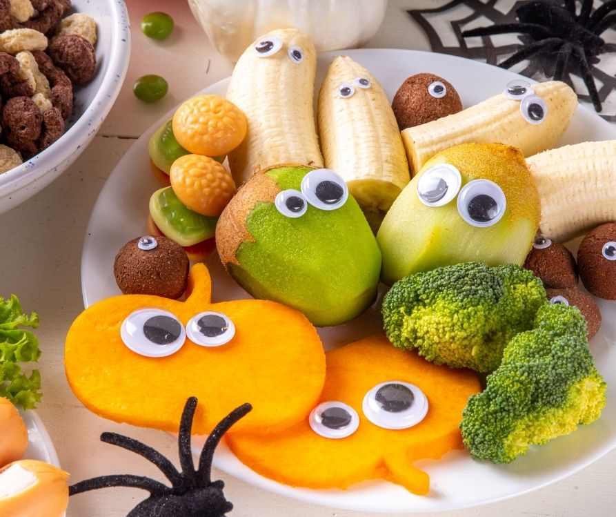 Halloween fruit, vegetables, and energy balls decorated with googly eyes.