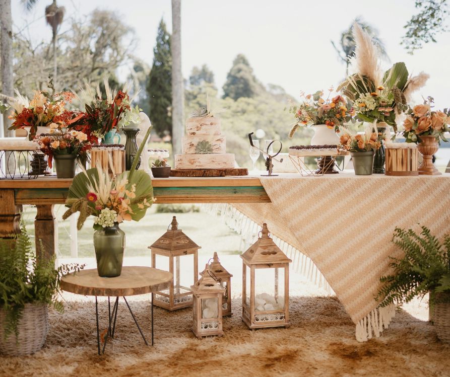A table set up in the shade next to lake decorated for a fall dinner party. Including candles, blankets, and fall foliage.